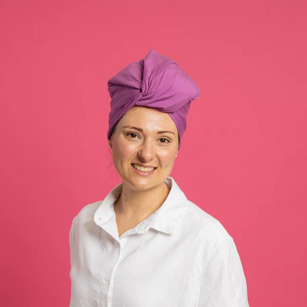 woman wearing purple silk lined tubular hair wrap (silk buff) against pink background