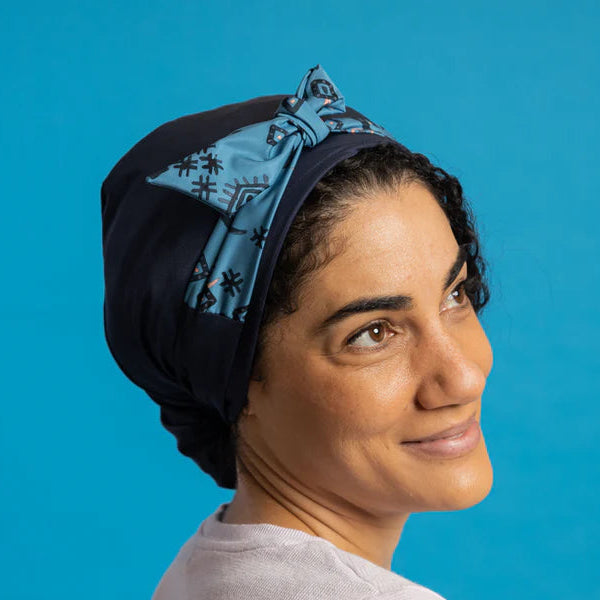 Woman wearing soft Shower Cap protecting curl hair against blue background. 