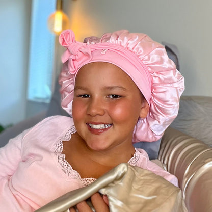 child wearing pink silk bonnet to protect curls overnight 