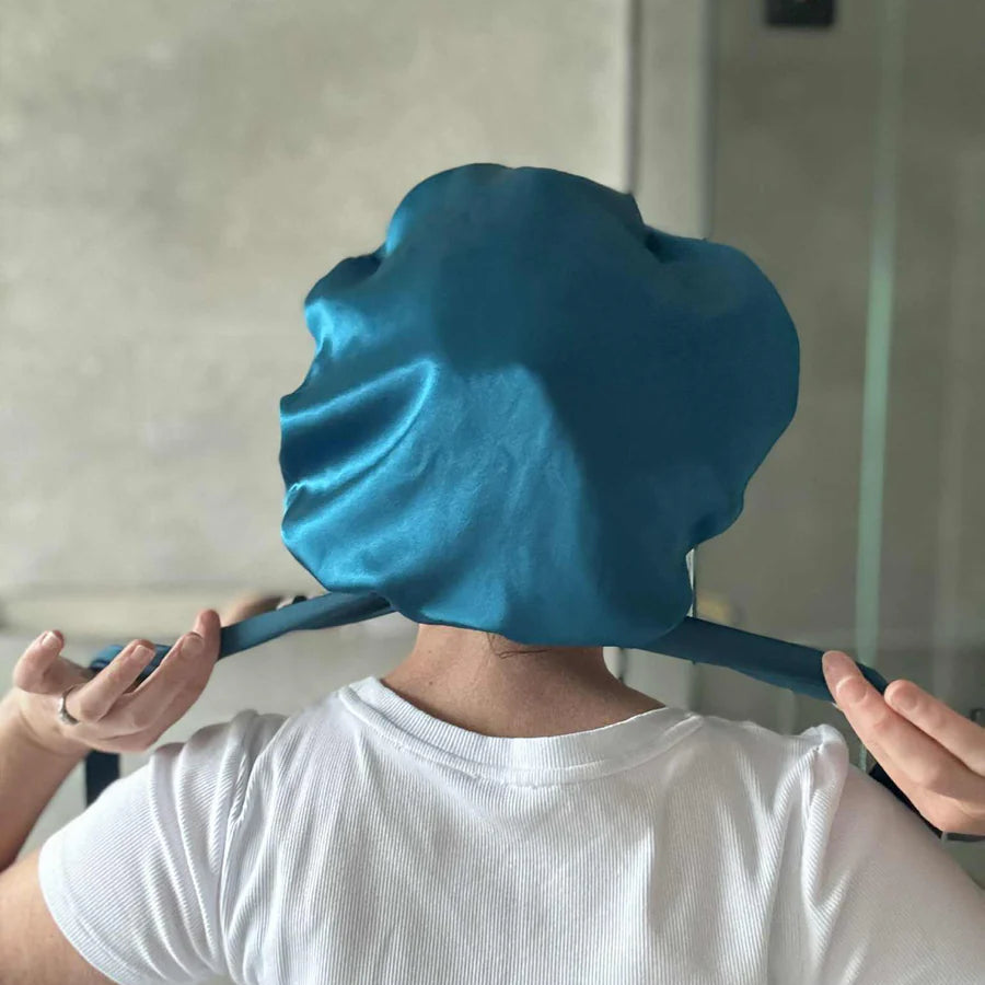 person wearing Lapis (teal) silk cap demonstrating the ties to secure the bonnet.