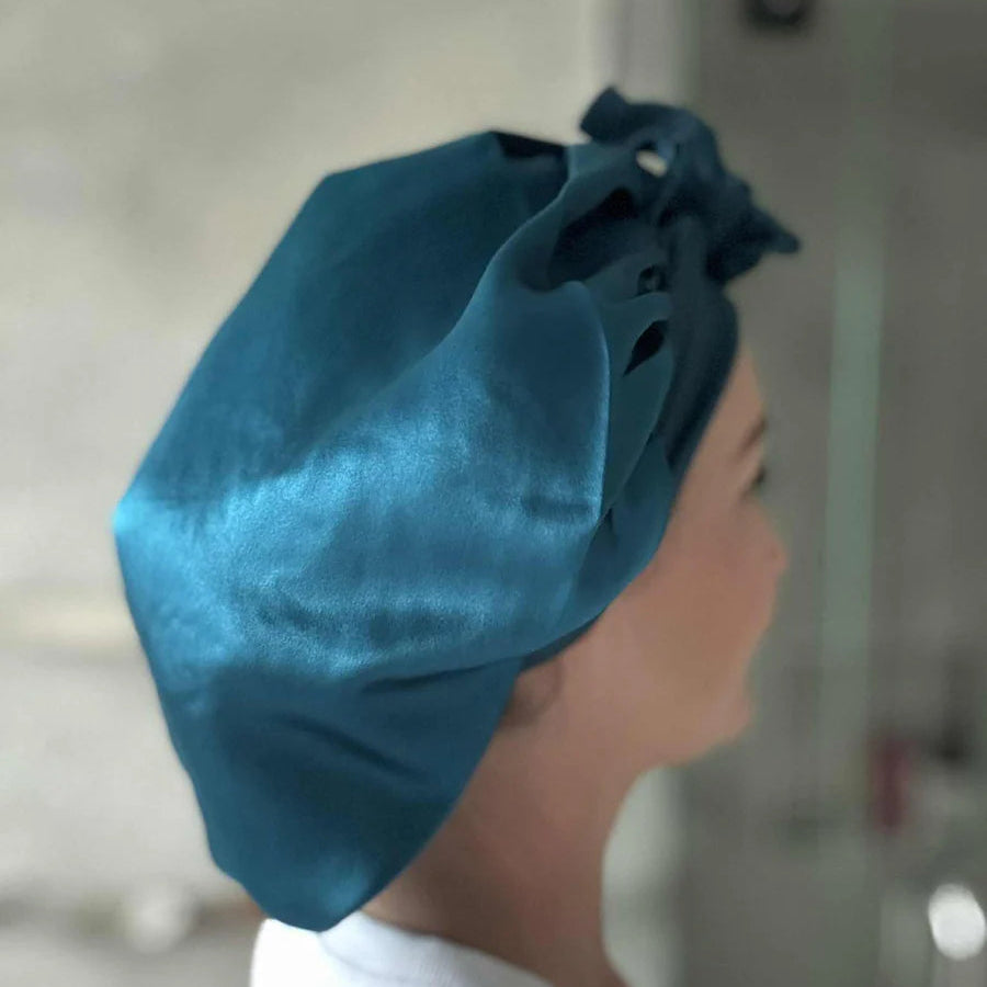 Person wearing a lapis (teal) coloured silk bonnet, side view
