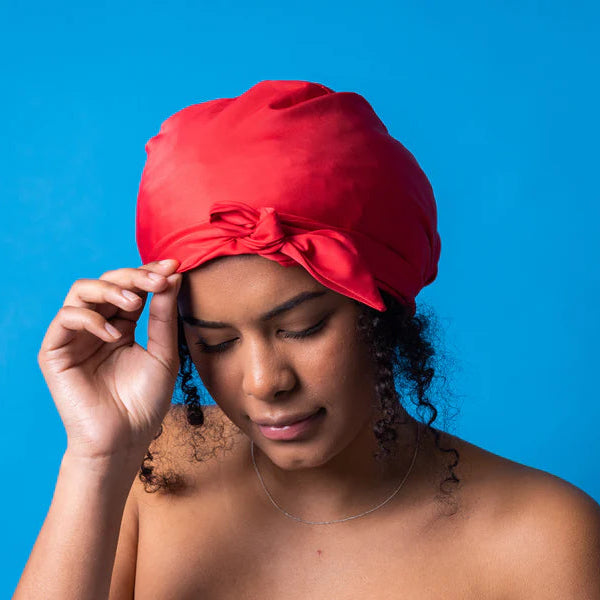 woman wearing red splash proof shower cap to protect curls 