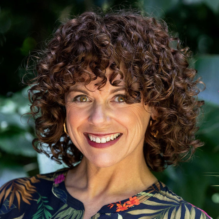 Woman with curly hair standing in front of green foliage, with text overlay 'The Curl Next Door' and 'Donna'.